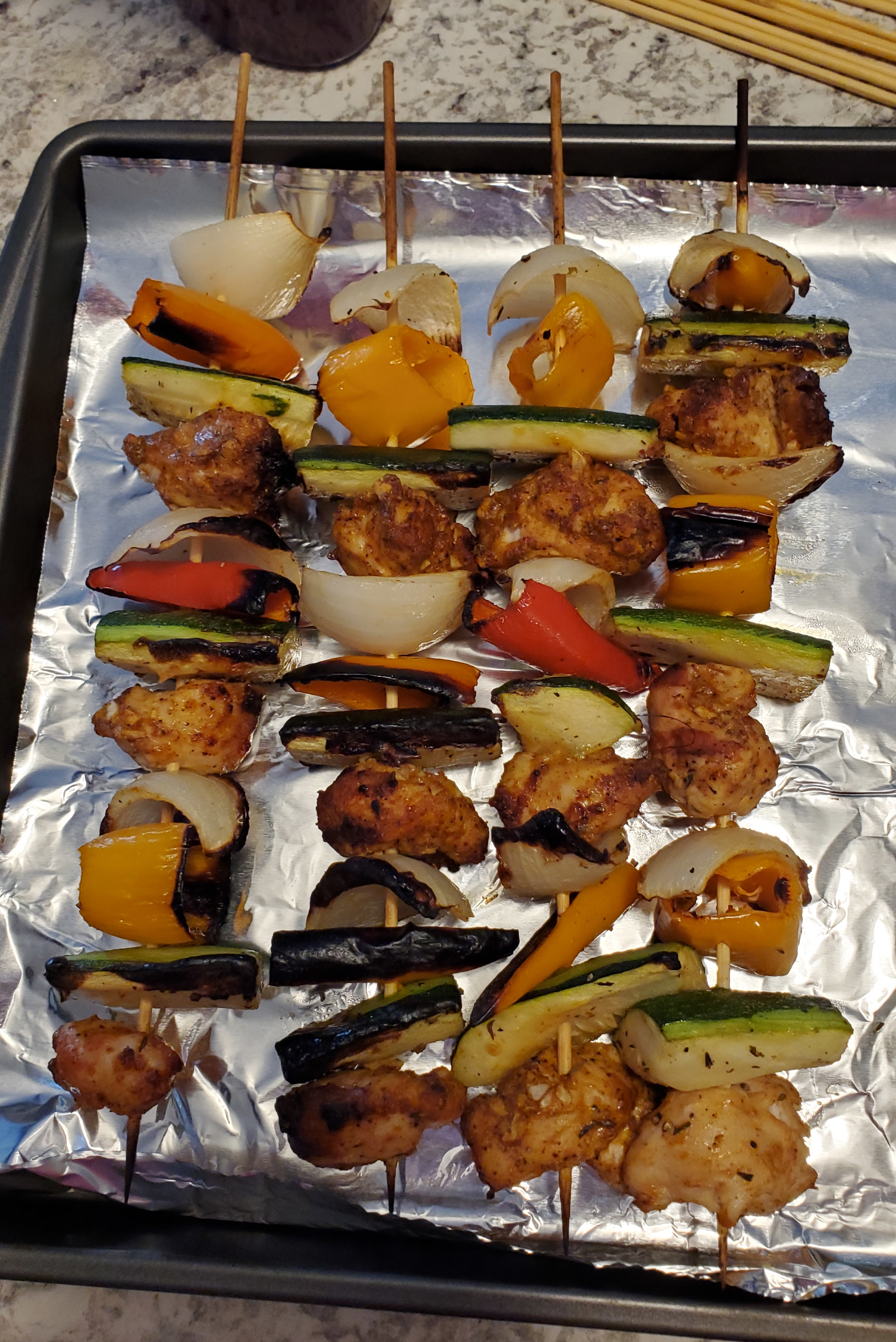 Chicken kebabs on a foil-lined baking sheet