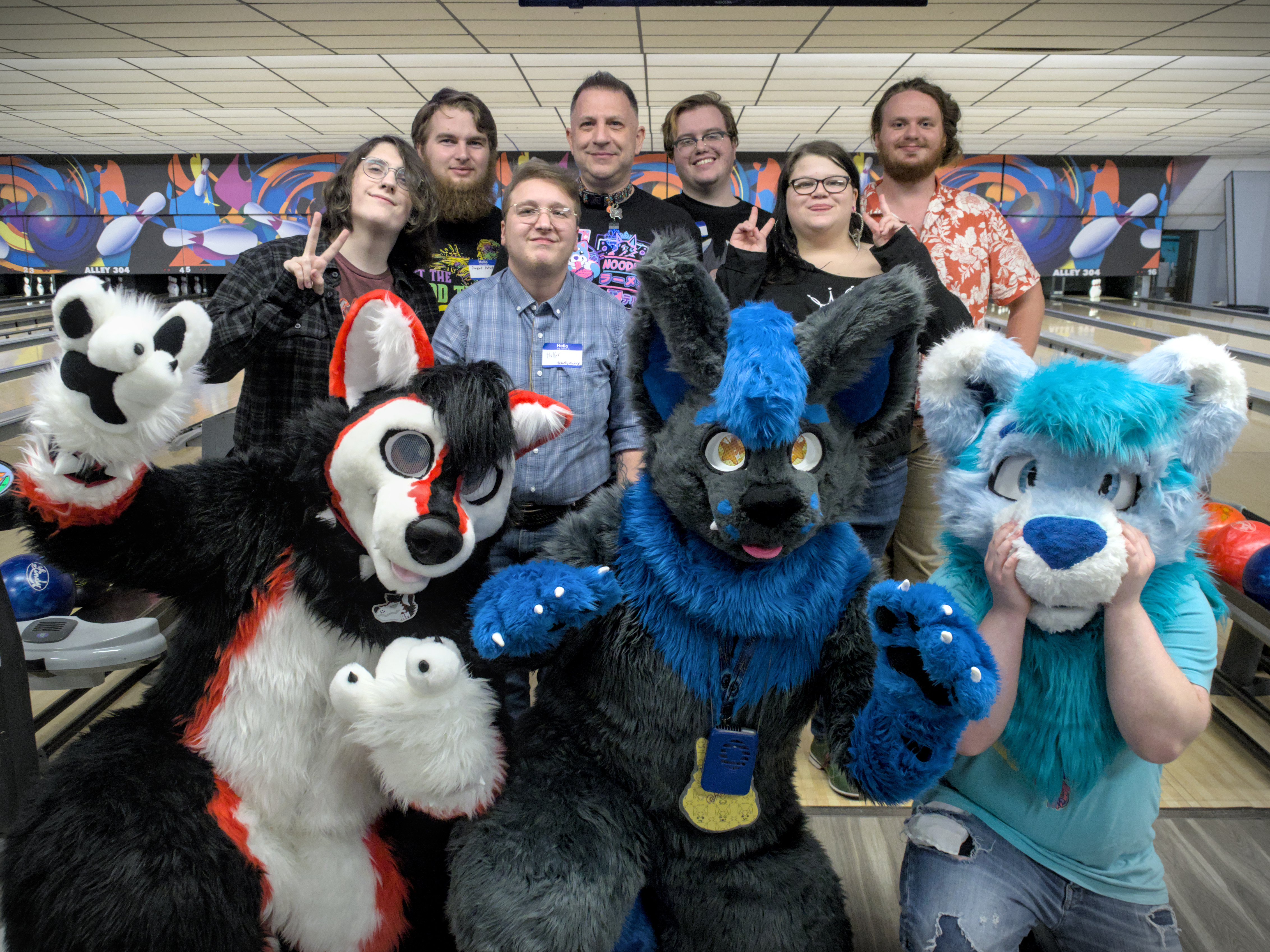 A group of people, including three in fursuits, posing for a photo at a bowling alley